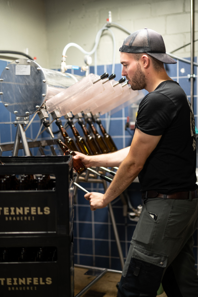 Mitarbeiter in der Brauerei Steinfels befüllt Bierflaschen